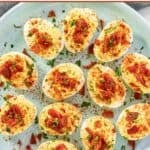 Candied bacon topped deviled eggs on a platter.