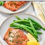 Lemon butter salmon served with green beans and lemon wedges.