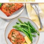 Salmon with lemon butter, green beans, and lemon wedges on two plate.