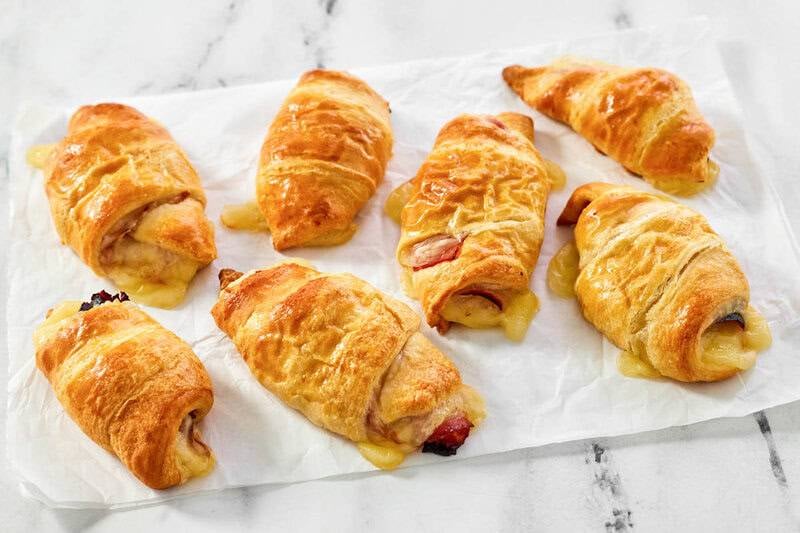 Ham and swiss cheese rolls freshly baked with cheese oozing out of them.