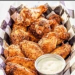 Homemade dry rub smoked chicken wings with dipping sauce in a serving basket.