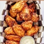 Dry rub smoked chicken wings and a cup of dipping sauce in a serving basket.
