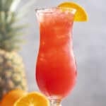 A fruity rum punch drink in a hurricane glass.