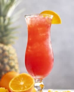 A fruity rum punch drink in a hurricane glass.