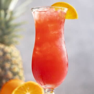 A fruity rum punch drink in a hurricane glass.