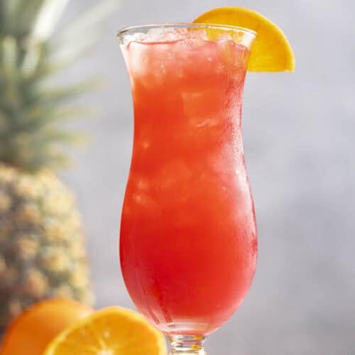 A fruity rum punch drink in a hurricane glass.