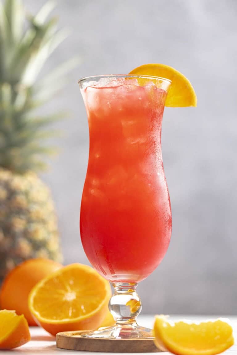 A fruity rum punch drink in a hurricane glass.