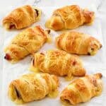 Flaky ham and Swiss cheese rolls on parchment paper.