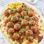 A platter of meatballs cooked with pepperoncini and gravy served over mashed potatoes.
