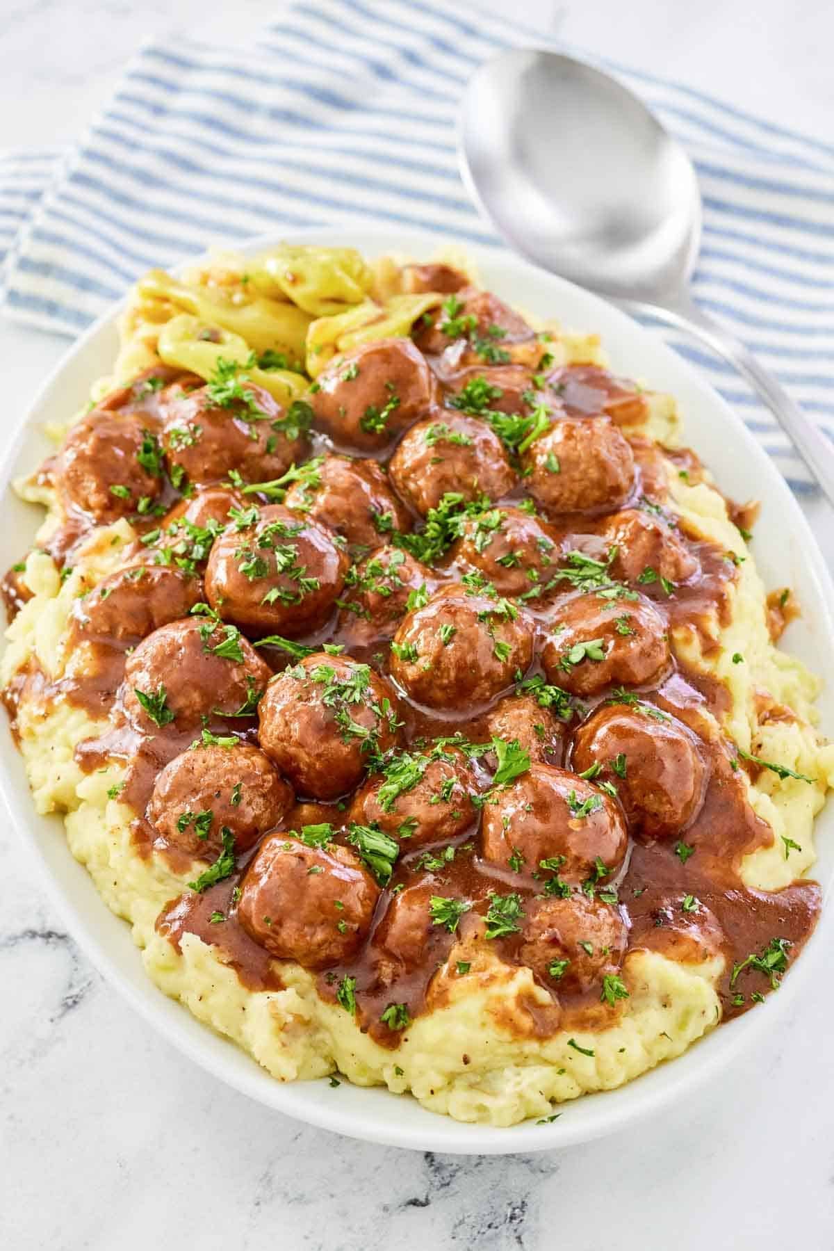 A platter of meatballs cooked with pepperoncini and gravy served over mashed potatoes.