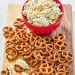 Homemade million dollar dip and mini pretzels on a wooden platter.
