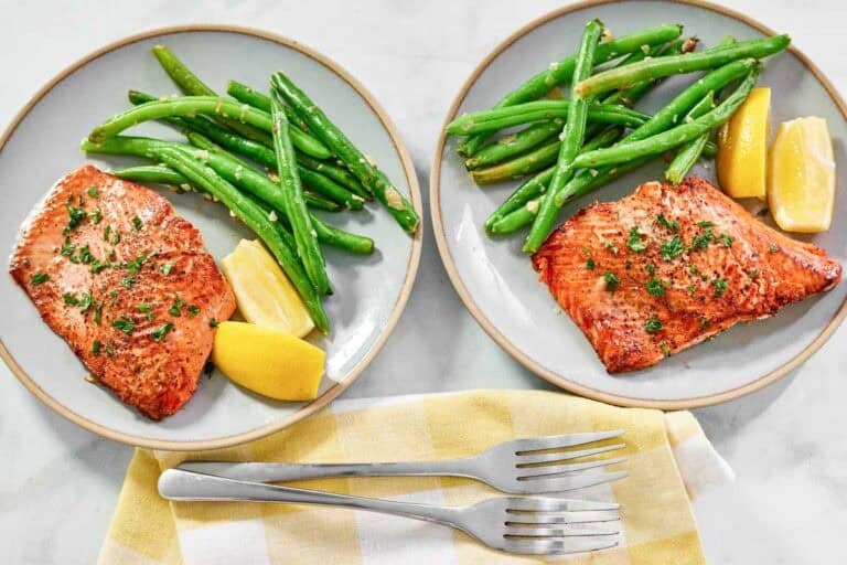 grilled salmon on a plate with green beans and cut lemons