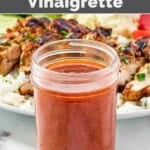 Copycat CAVA hot harissa vinaigrette in a mason jar in front of a grilled chicken salad.