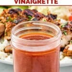 Copycat CAVA hot harissa vinaigrette in a mason jar and grilled chicken over rice behind.