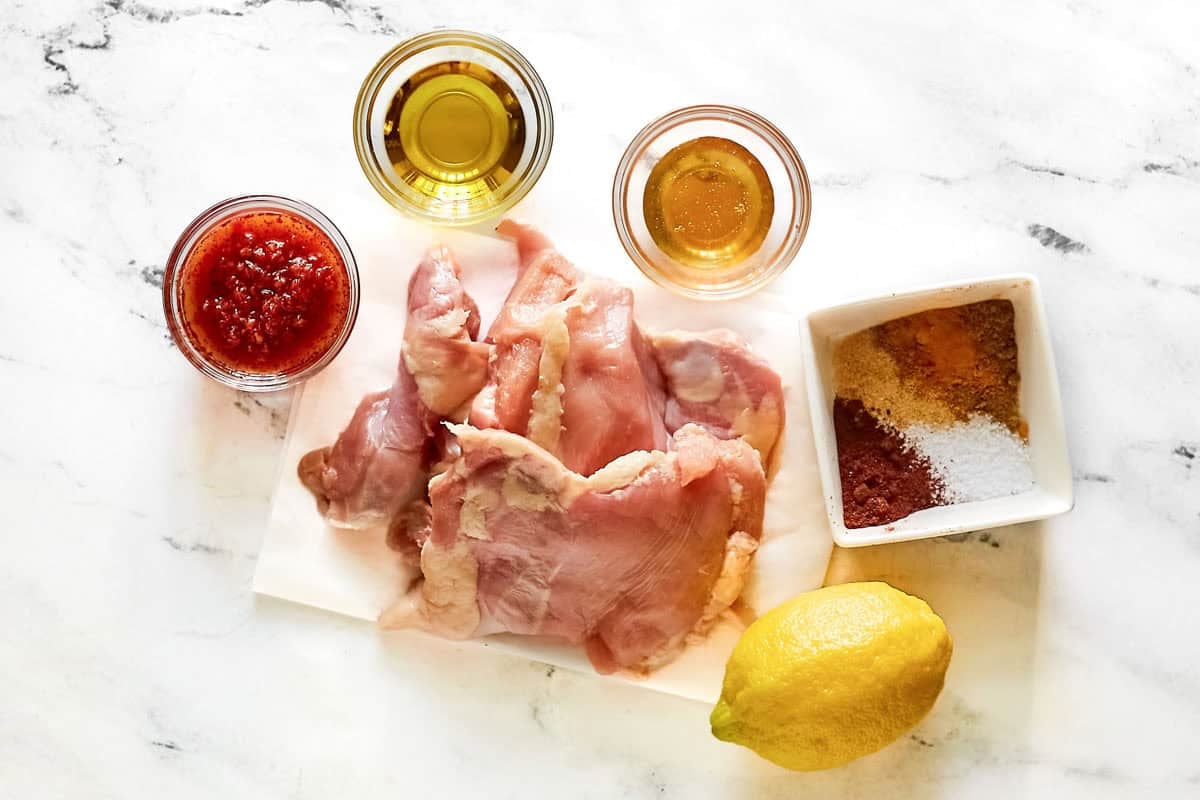 Chicken thighs, harissa, honey, oil, lemon, vinegar, and spices.