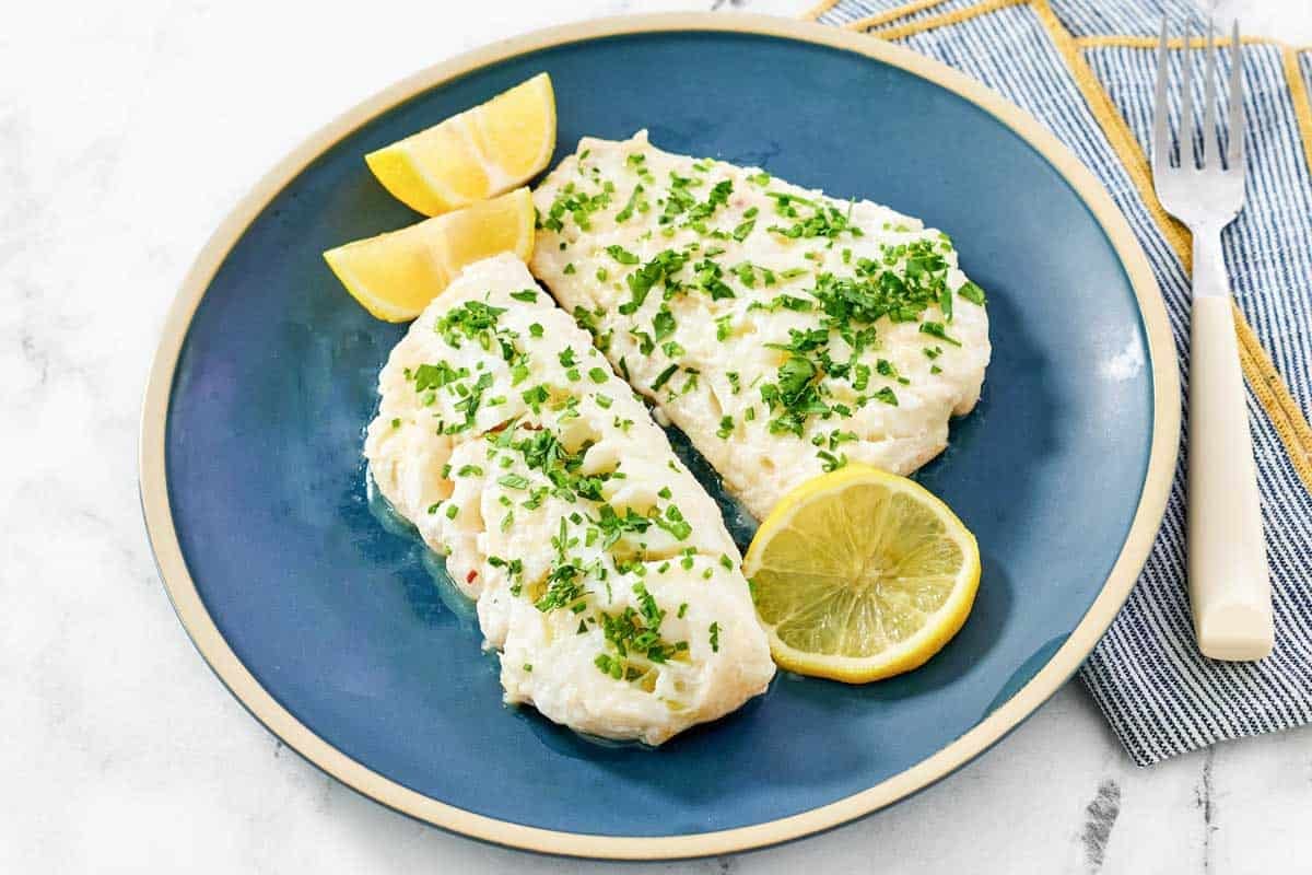 Cooked white fish fillets with lemon butter and herbs.