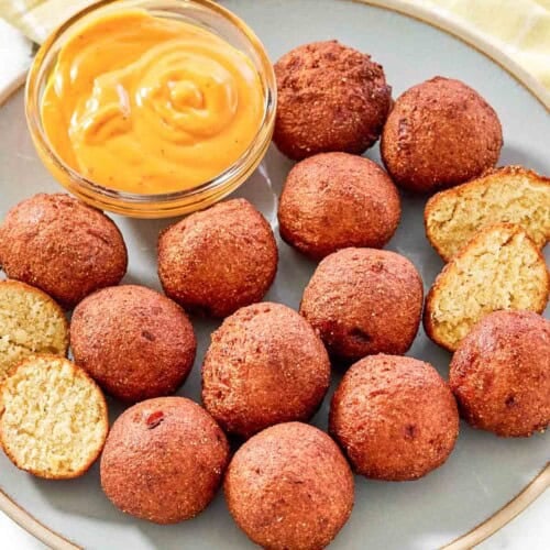 Fried cornbread hush puppy balls served with dipping sauce.