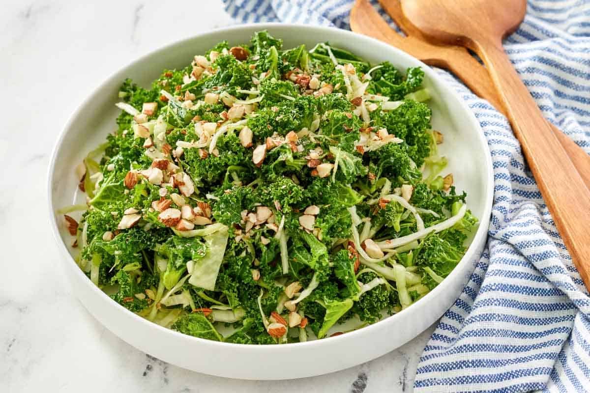 A kale, cabbage, and almond salad in a large bowl.