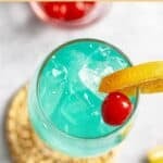 Copycat Olive Garden blue capri cocktail garnished with a cherry and orange slice.