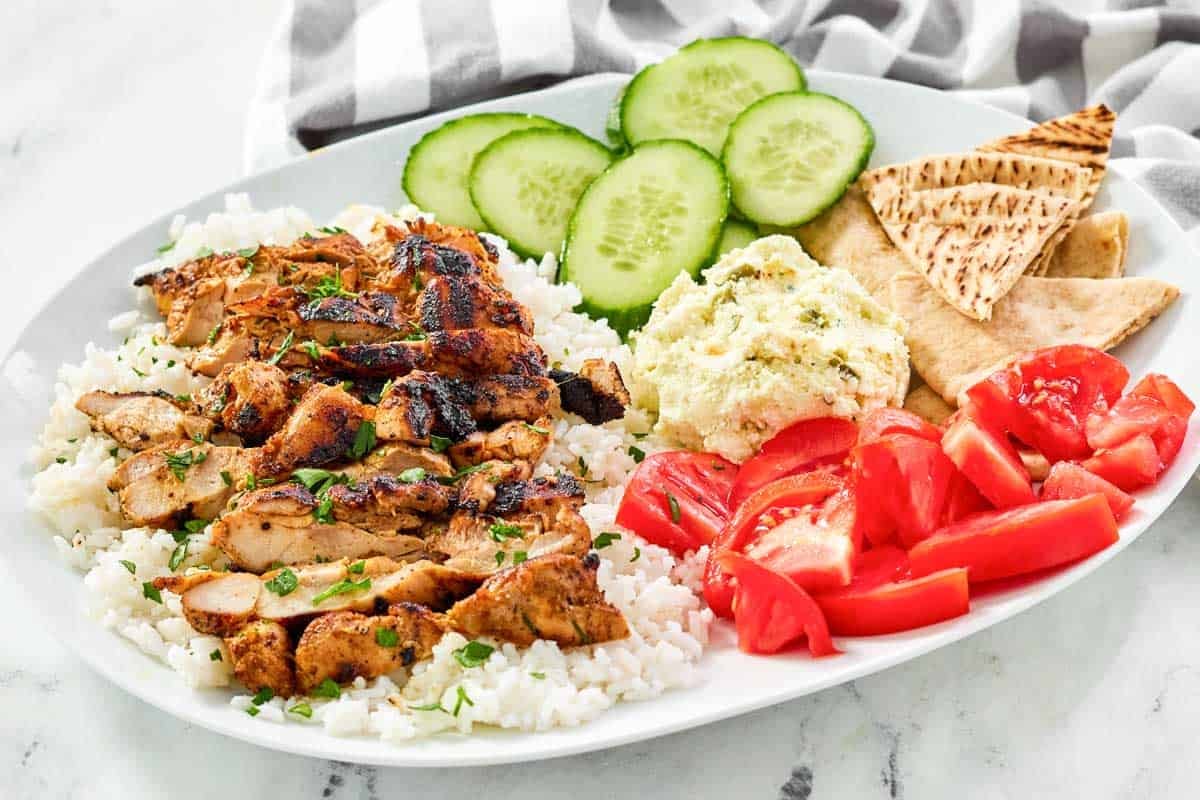 Spicy Mediterranean grilled chicken strips served over rice with feta, veggies, and pita bread.