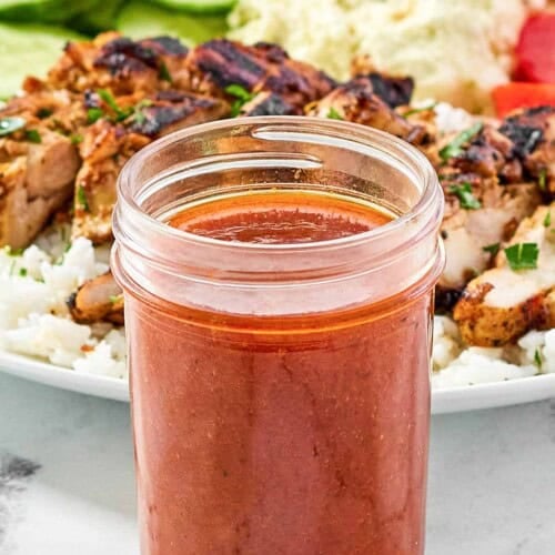 Spicy Mediterranean vinaigrette and a grilled chicken salad behind it.
