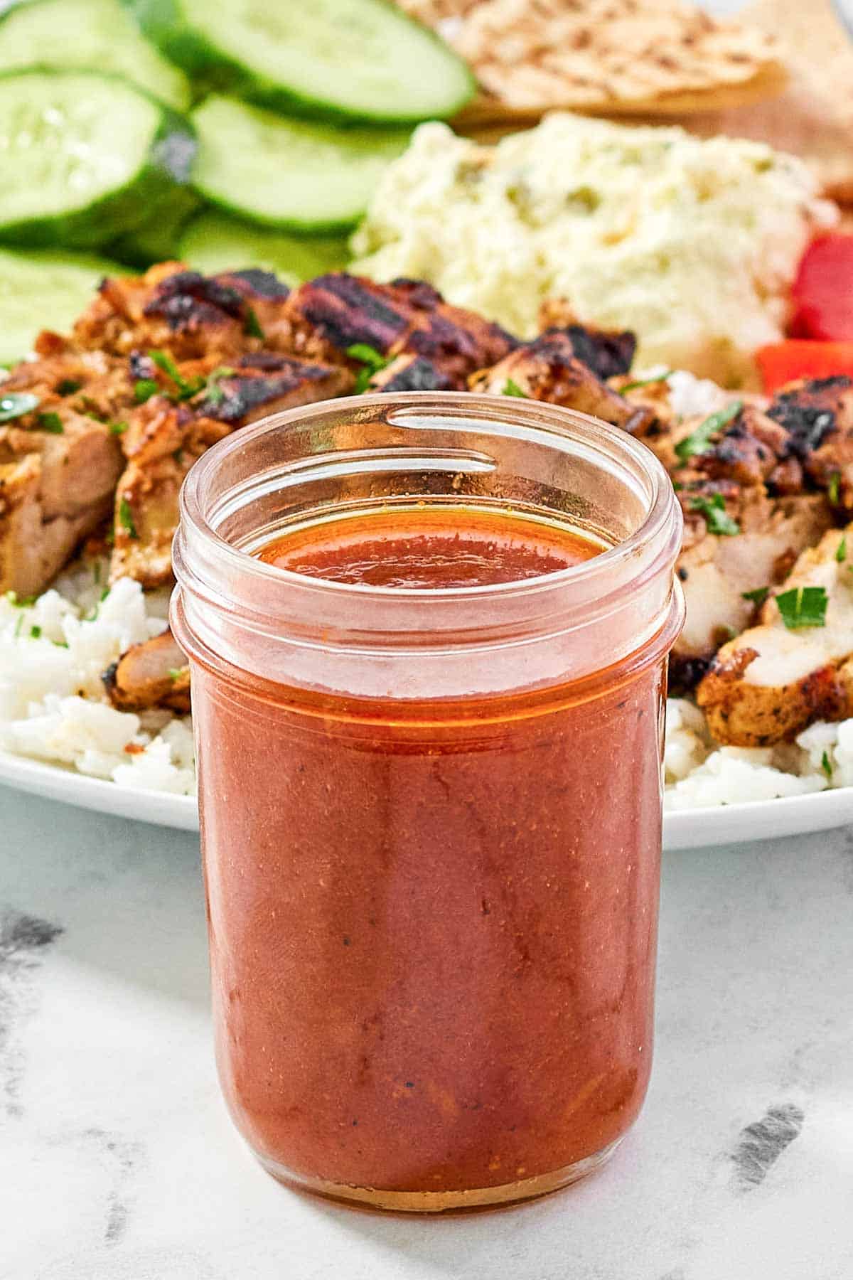 Spicy Mediterranean vinaigrette and a grilled chicken salad behind it.