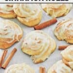 Copycat Cinnabon bread machine cinnamon rolls and cinnamon sticks on parchment paper.