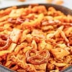 A bowl of homemade cheddar Chex mix with pretzels, Cheez-its, and Cheetos.