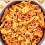A bowl of cheddar chex mix with Cheez-its, Cheetos, and pretzels.