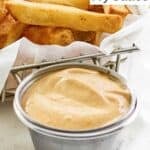 A small cup of Freddy's fry sauce and French fries.
