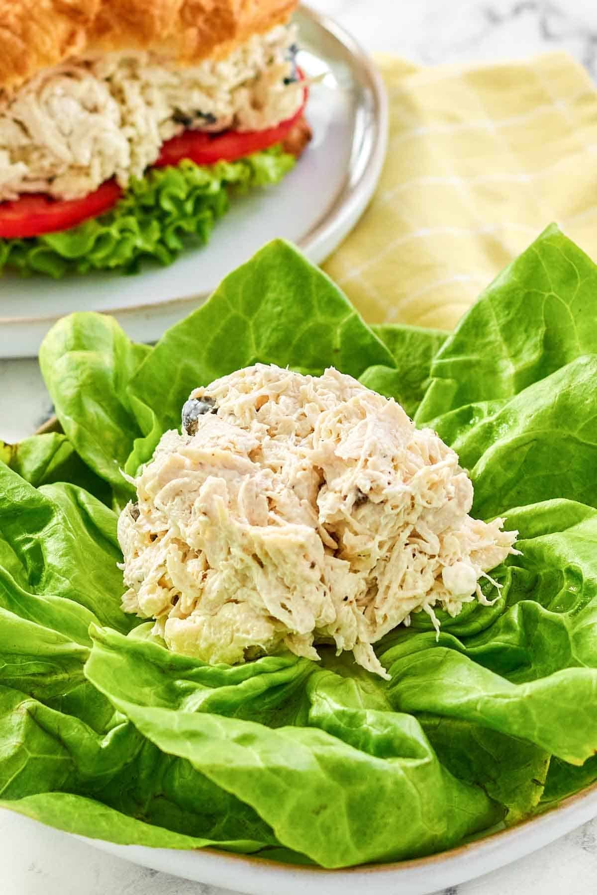 A scoop of Greek chicken salad served on butter lettuce leaves.