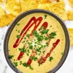 Green chile and tomatillo cheese dip served over guacamole.