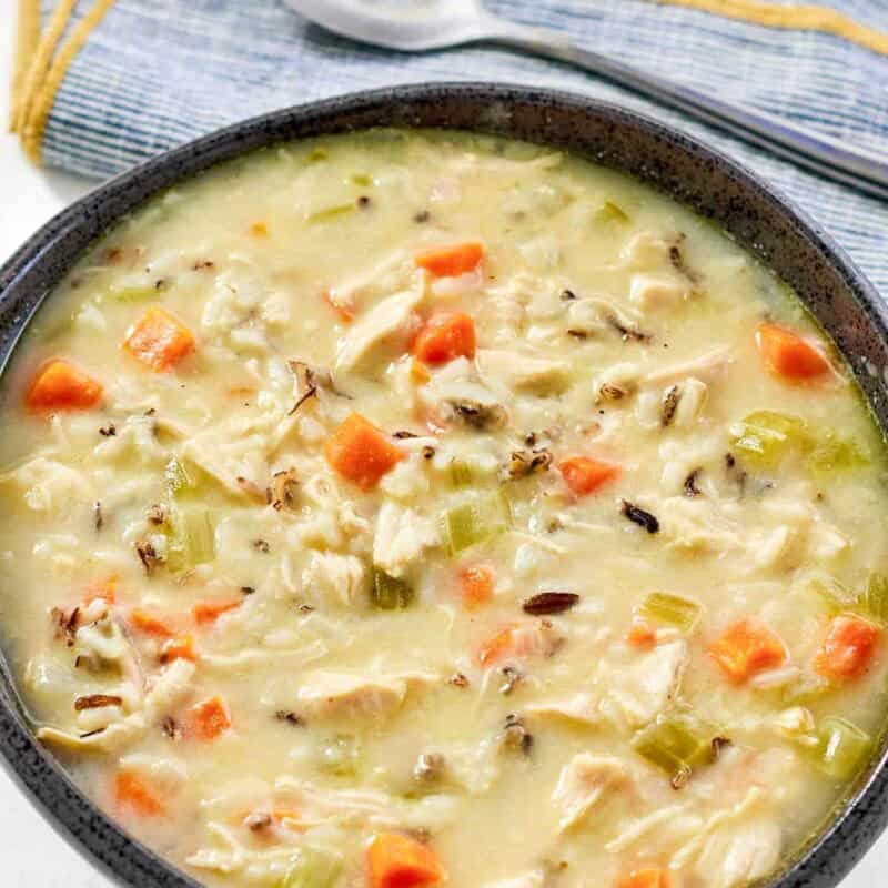 A bowl of creamy soup with wild rice, chicken, and vegetables.