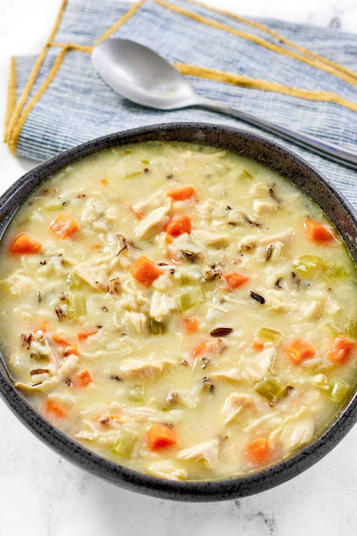 A bowl of creamy soup with wild rice, chicken, and vegetables.