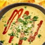 Copycat Torchy's green chile queso topped with cotija cheese, hot sauce, and cilantro.