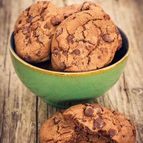 Chocolate chocolate chip cookies in a bowl and in front of it.