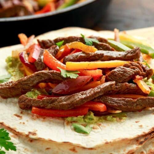 Steak fajitas on top of tortillas.