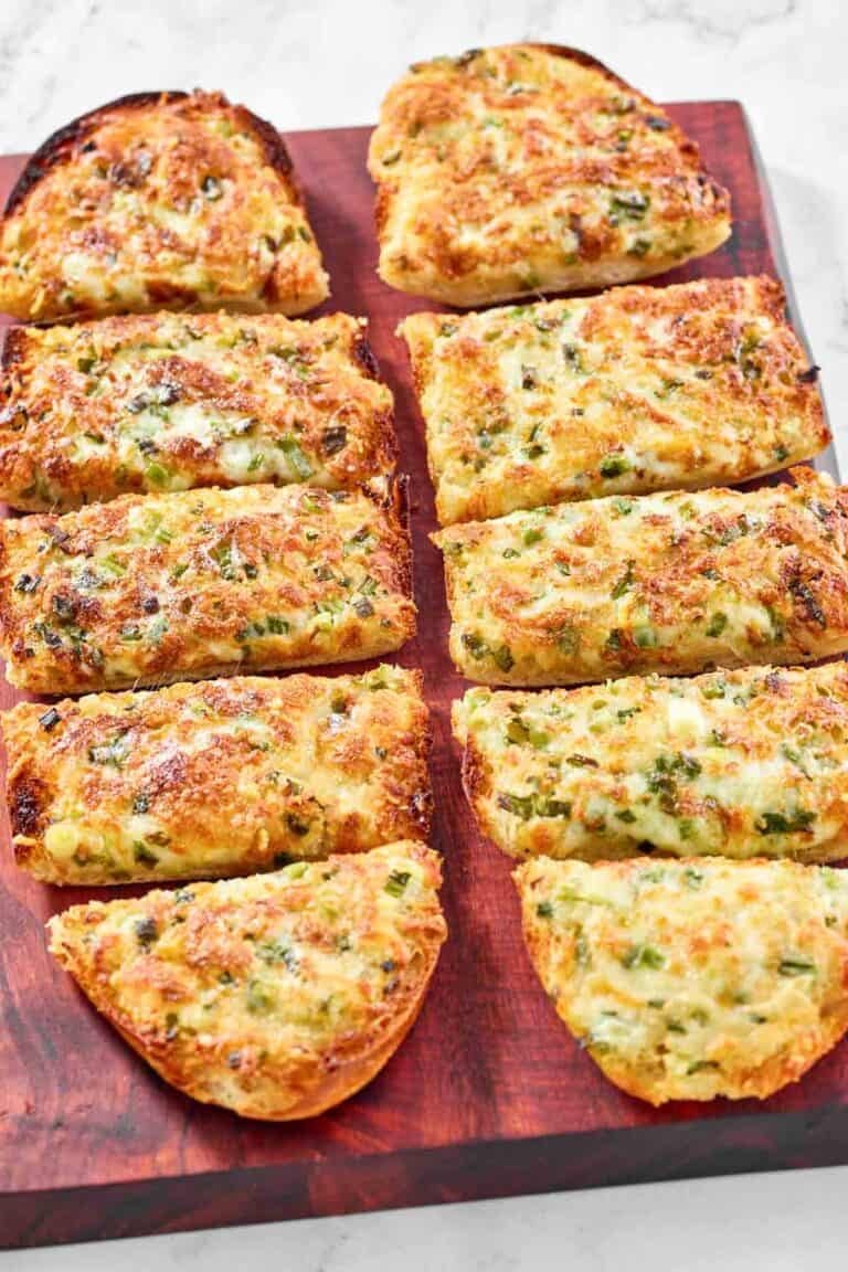 Green onion and garlic cheese bread slices on a serving board.