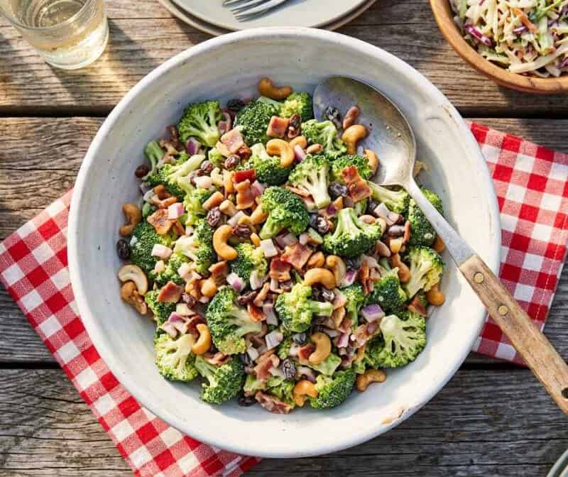 a bowl of creamy broccoli salad on a picnic table