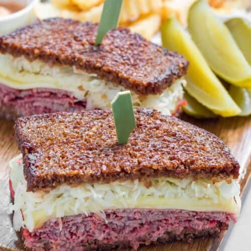 A classic reuben sandwich served with fries and pickle slices.
