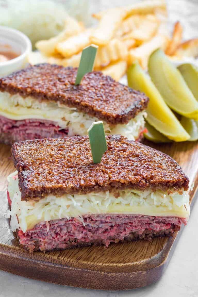 A classic reuben sandwich served with fries and pickle slices.