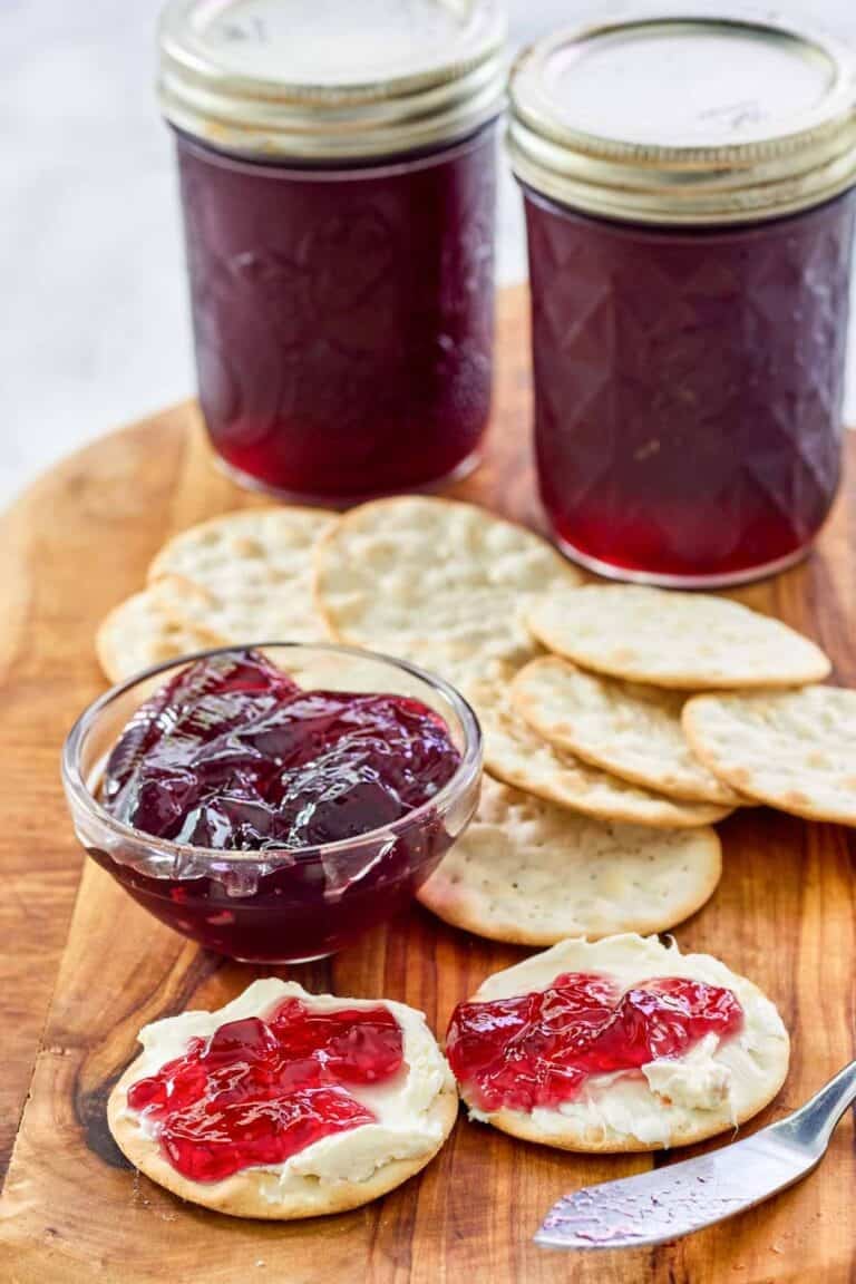 Red wine jelly in jars, in a small cup, and on top of cream cheese crackers.