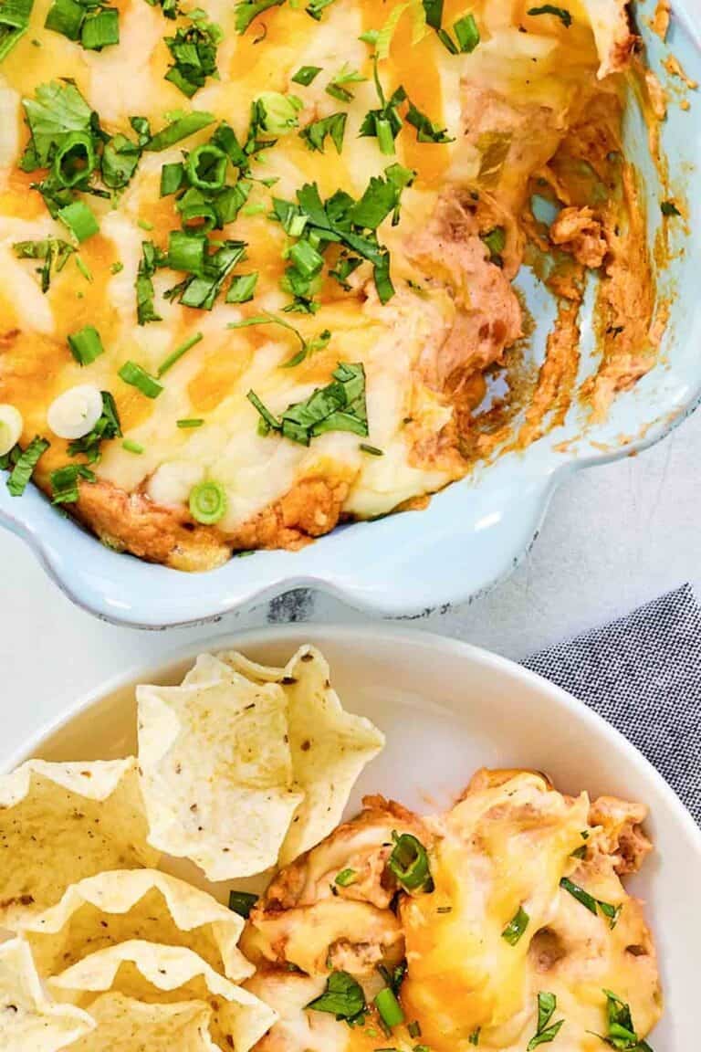 Refried bean cream cheese taco dip in a baking dish and served with tortilla chips.
