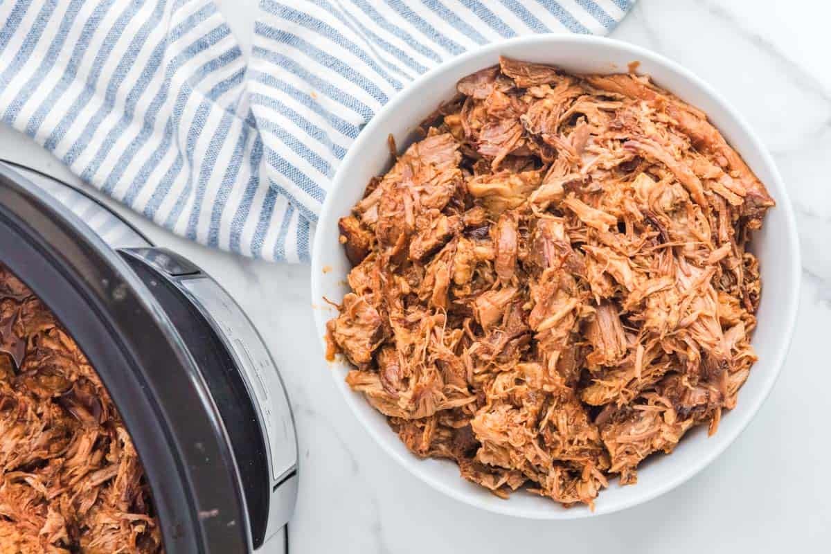 Shredded barbecue pork in a bowl and slow cooker.