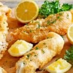 Copycat Captain D's battered fish served with lemon wedges and garnished with parsley.