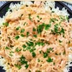 A plate of crockpot chicken and rice over gravy.