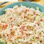 A bowl of copycat Popeyes coleslaw and a spoon resting on a napkin.