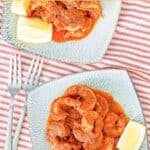 Copycat Red Lobster Cajun shrimp and lemon wedges on two plates.