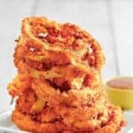 Copycat Red Robin onion rings stacked high on a plate.