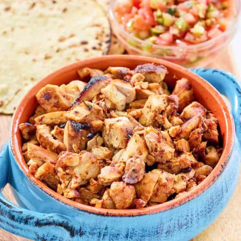 Adobo, chipotle, anchiote pepper, and fruity chicken pieces in a bowl.